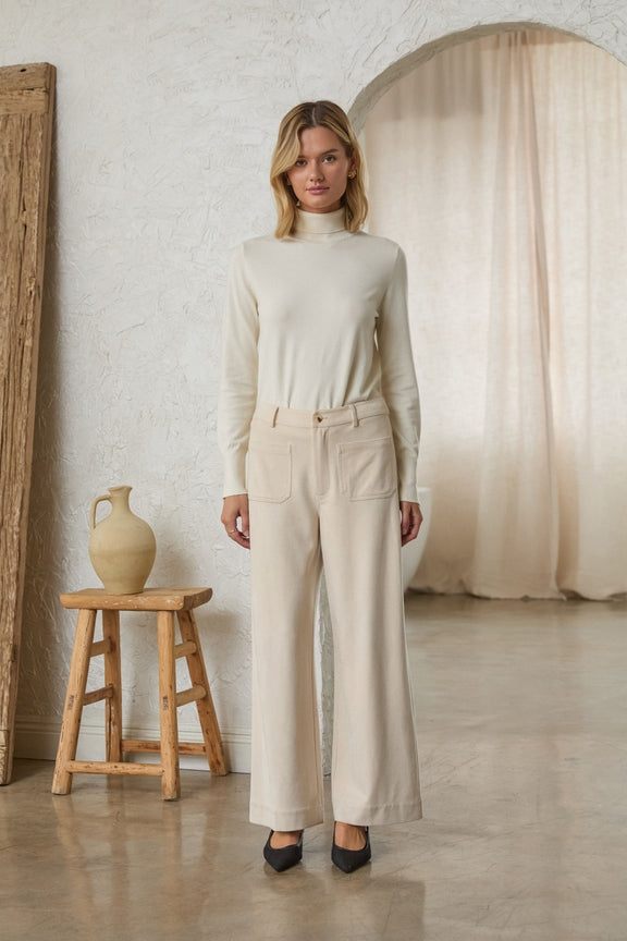 Woman wearing cream Lucy Faux Suede Wide Leg Pants with front pockets and a matching turtleneck.