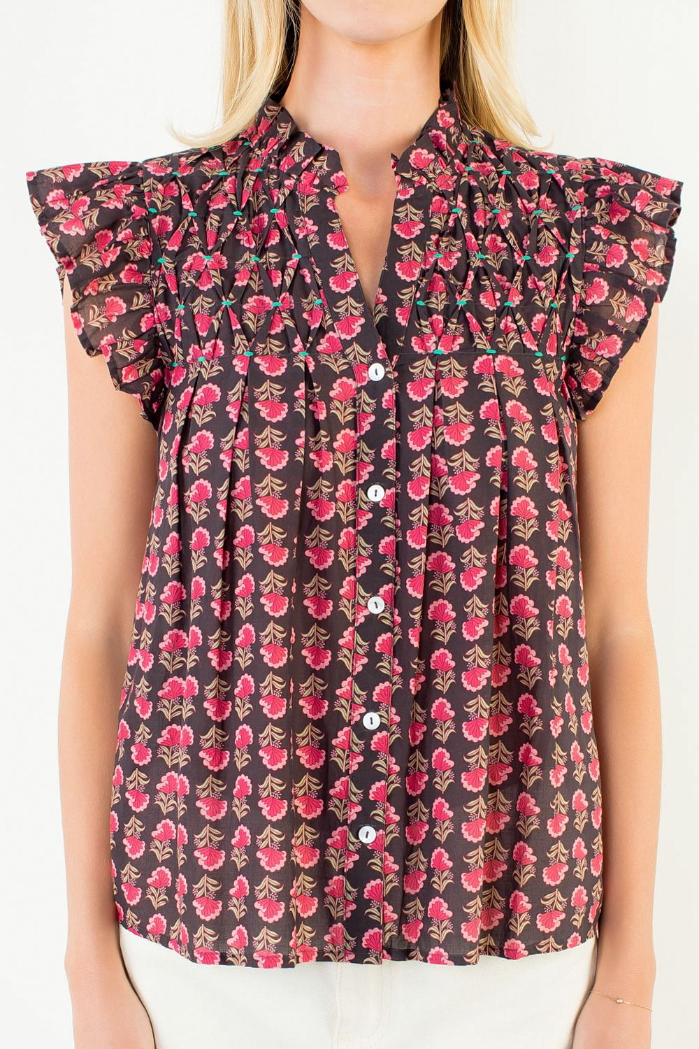 Woman wearing a Jane Flutter Sleeve Button Top with a pink floral print and smocked chest detail.