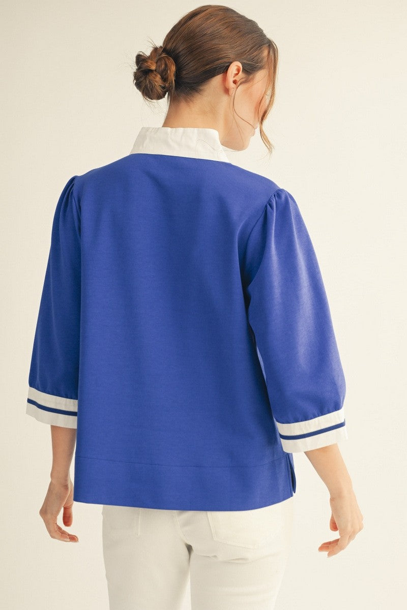 Solid top with standing neck, three-quarter sleeves, side slit hem, and color contrast accent.