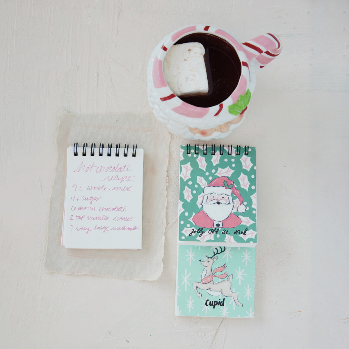 Top view of a hand-painted ceramic Santa head mug filled with hot chocolate and a large marshmallow.