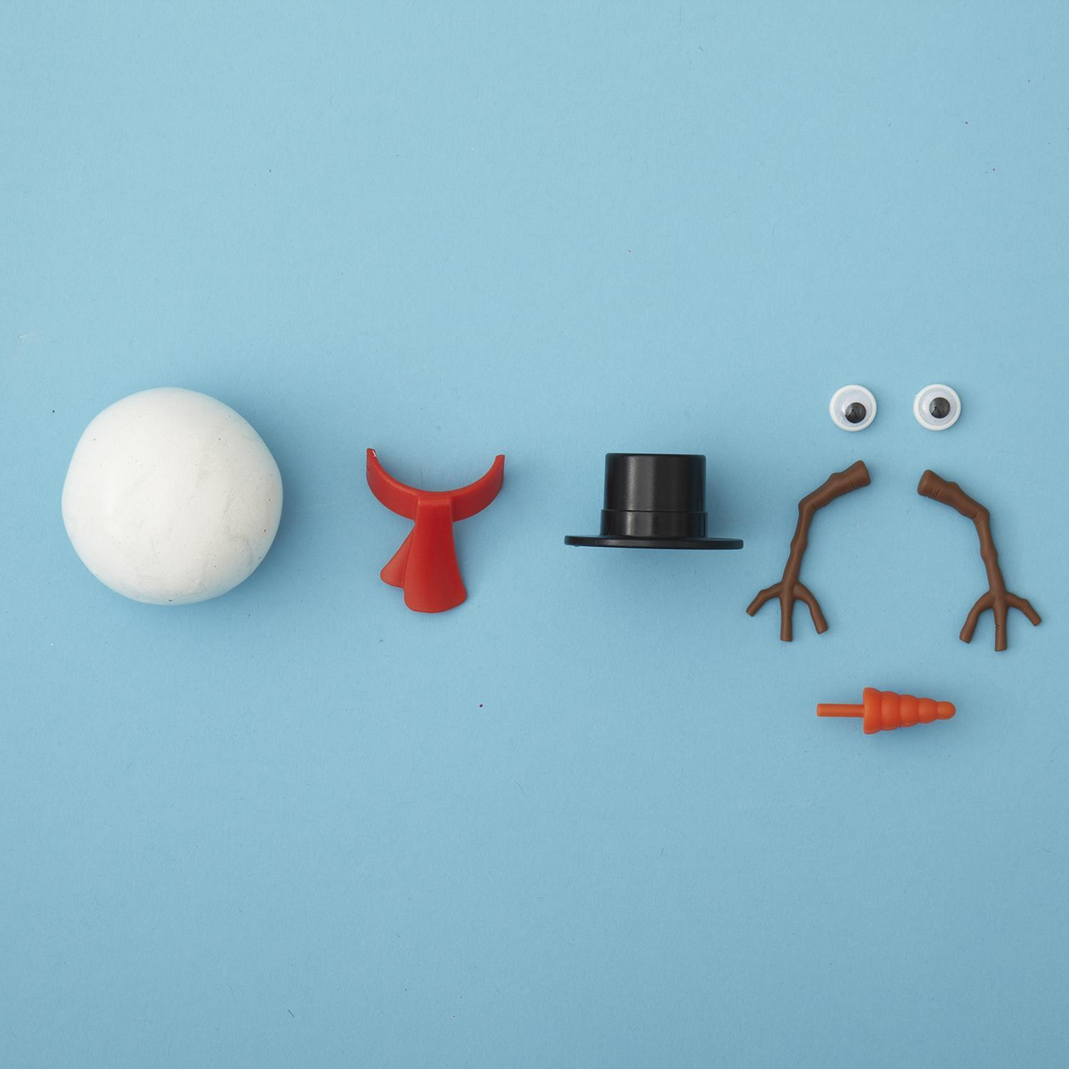 Miracle Melting Snowman kit with white putty, red scarf, black top hat, eyes, arms, and carrot nose.