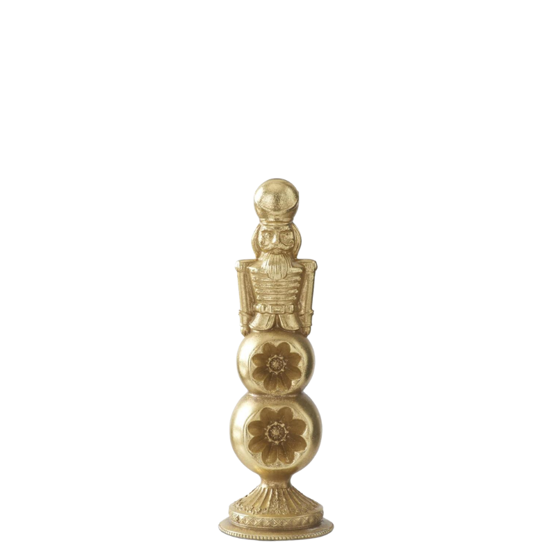 Gold nutcracker figure standing on a tiered ornament finial base with carved floral details.