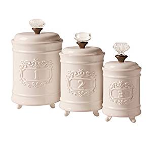 Set of three cream-colored ceramic canisters with ornate embossed numbers 1, 2, and 3 and decorative glass knobs.