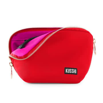 Red fabric Everyday Makeup Bag with gold hardware, three-side zipper opening, interior mesh pockets, and Kusshi logo.