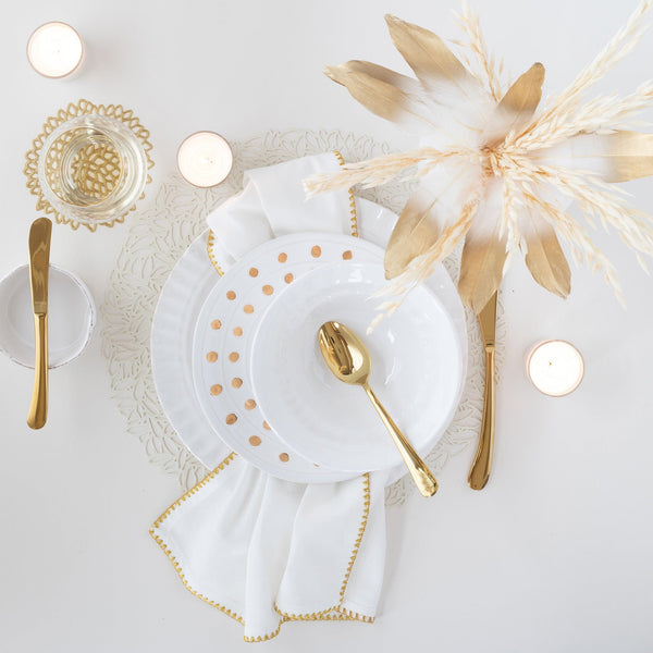 Medici Gold Salad Plate with gold polka dots on a white table setting with gold cutlery.