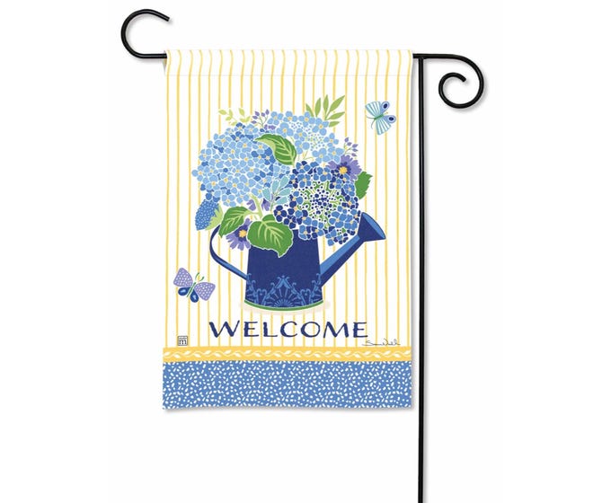 Blue hydrangeas in a watering can on a yellow striped garden flag with butterflies and the word WELCOME.