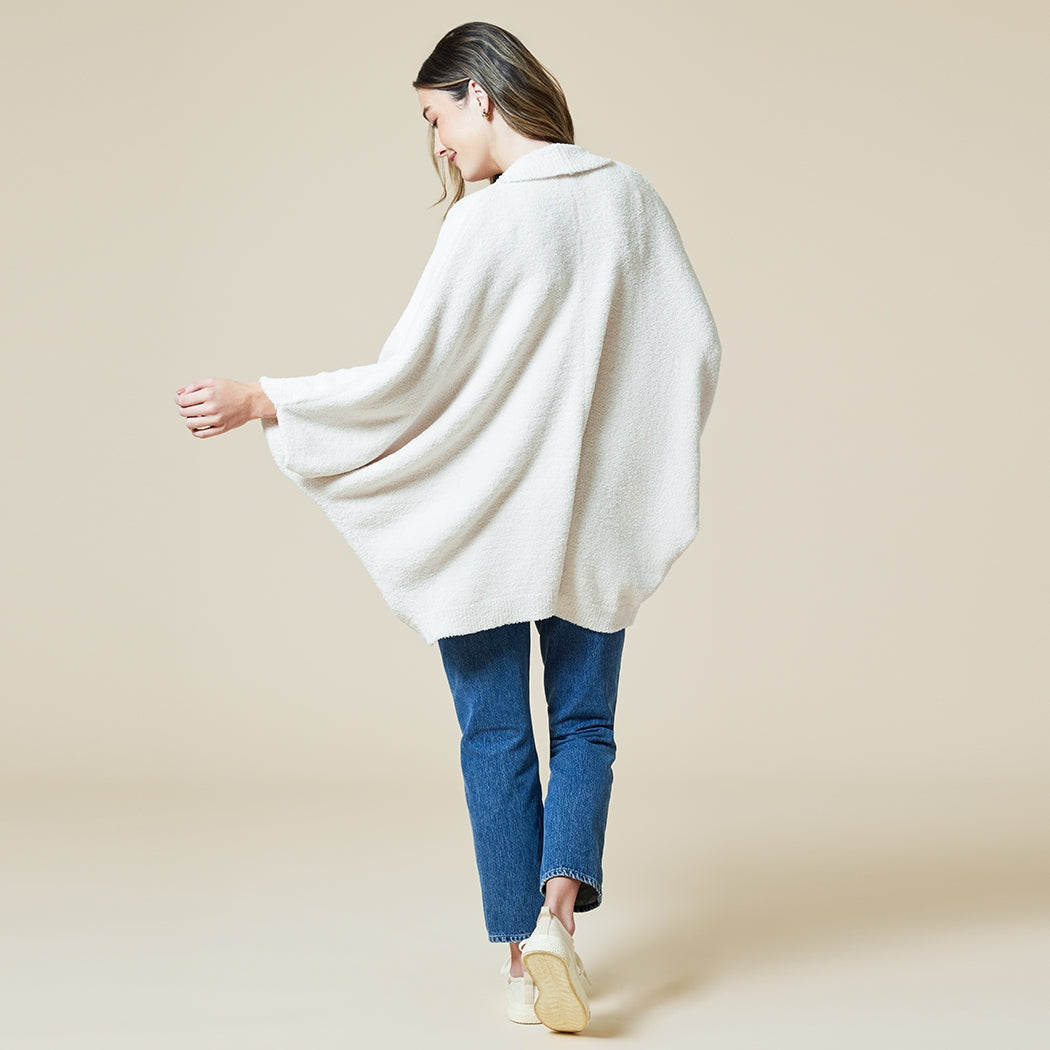 Woman from behind wearing a Solid Marshmallow Shrug in Almond with blue jeans and white sneakers.