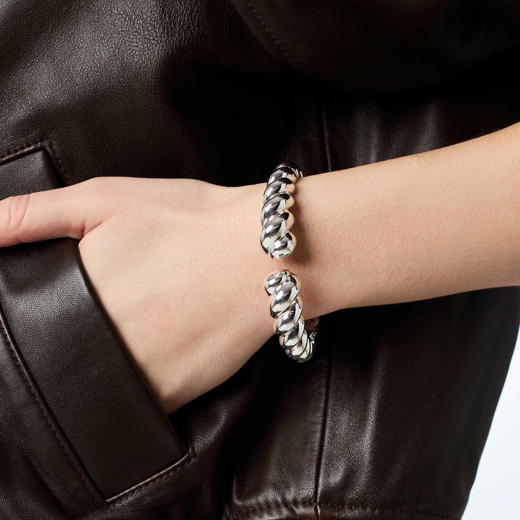A person wearing the Ravello Cuff Silver, a thick, twisted silver-tone open cuff bracelet.