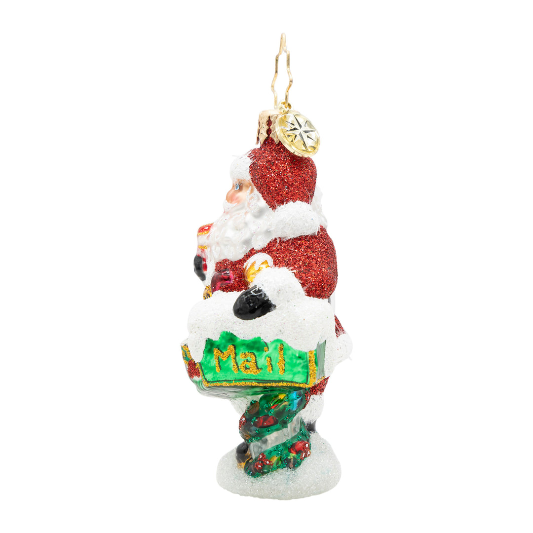 Santa Claus glass ornament holding a green mailbox with 'Mail' written in gold glitter.