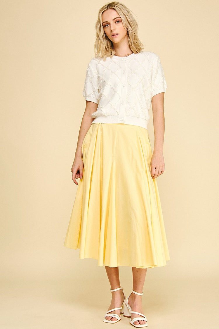 Amelia white short sleeve cardigan with a textured diamond pattern paired with a yellow midi skirt.