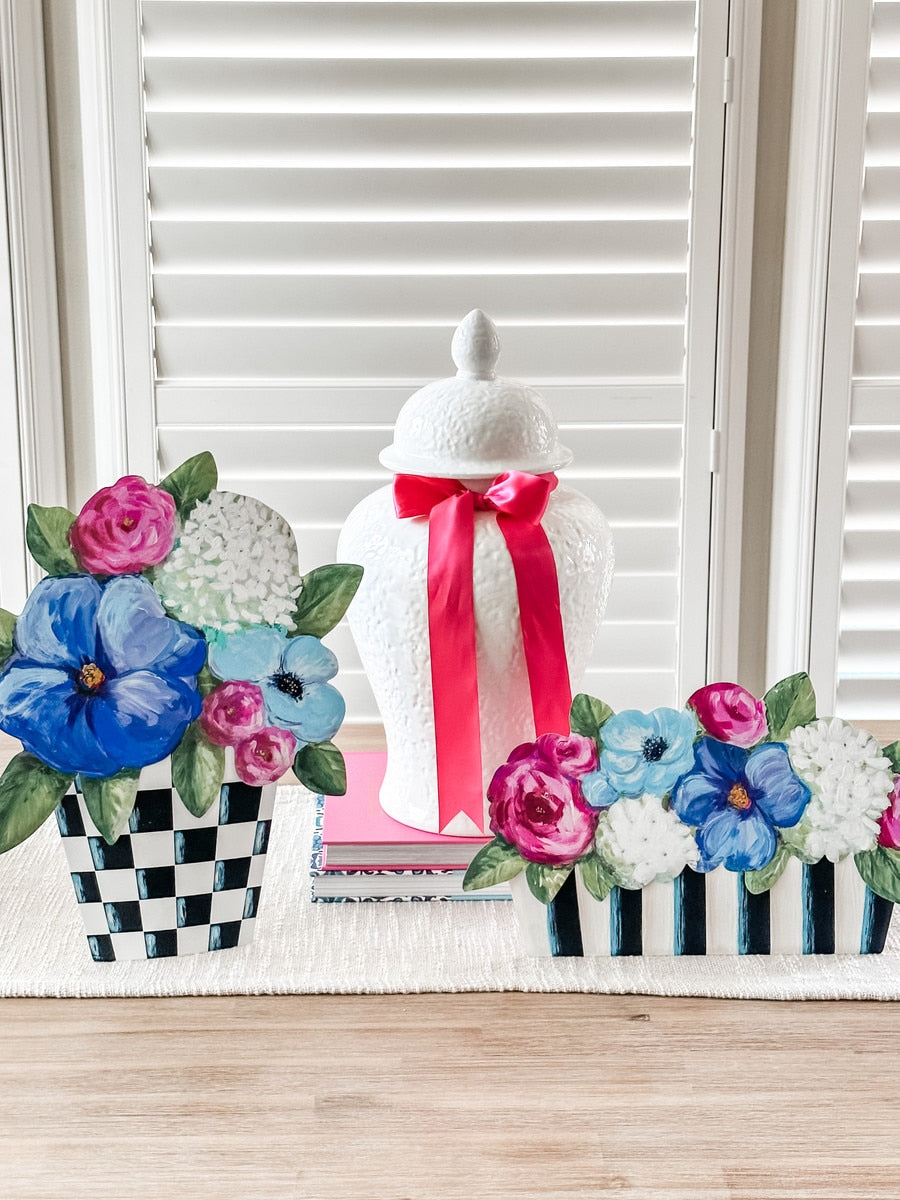 Elegant pots holding a mixed arrangement of colorful flowers displayed on an easel.