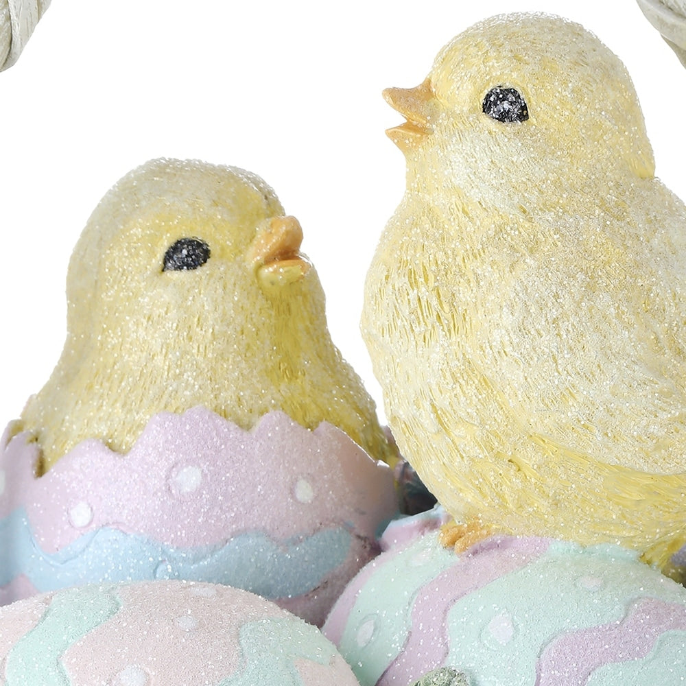 Close-up of two yellow resin chicks in pastel Easter egg shells with glitter accents.