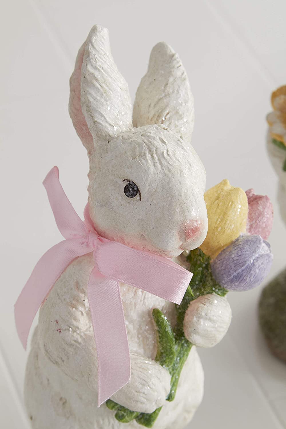 Polyresin bunny figurine in pink with a bow holding flowers