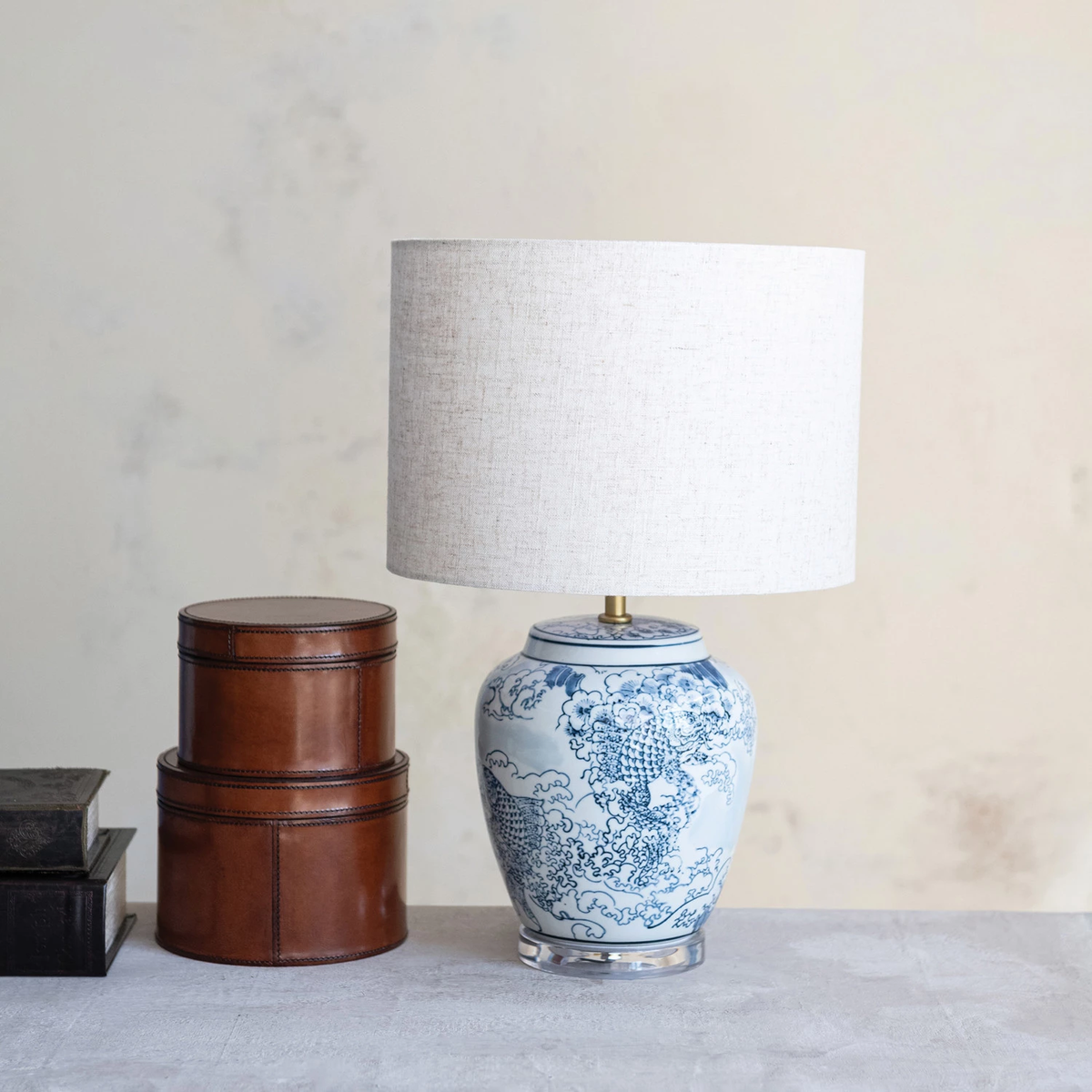 Hand-painted ceramic table lamp with a round shade in neutral tones.