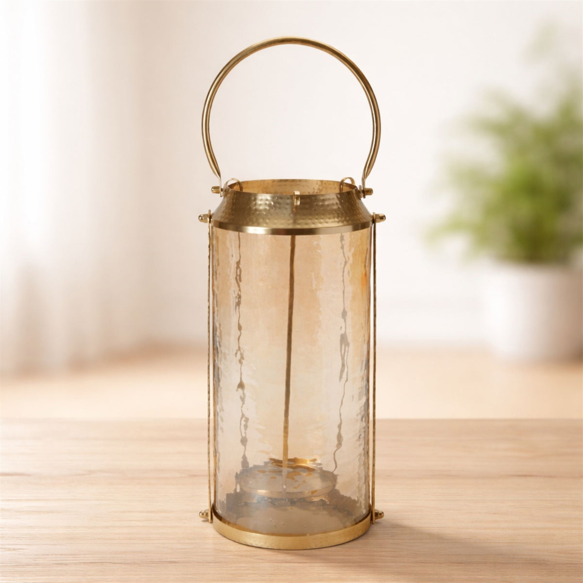 7.25-inch hammered glass lantern with a brushed brass frame and a curved handle on a wooden table.