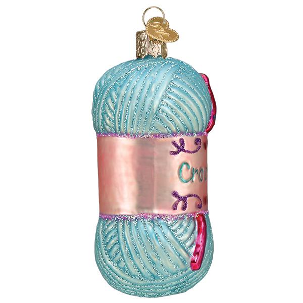 Light blue glittery yarn skein glass ornament with a pink label and crochet hook detail.