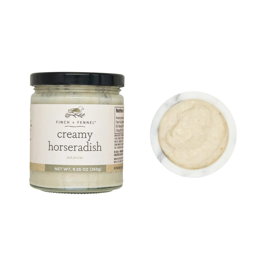 A jar of Finch + Fennel Creamy Horseradish Sauce next to a small marble bowl of the sauce.