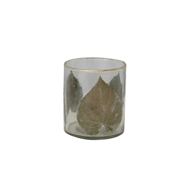 Hand-blown glass votive holder with embedded Peepal leaves and a gold foil rim.