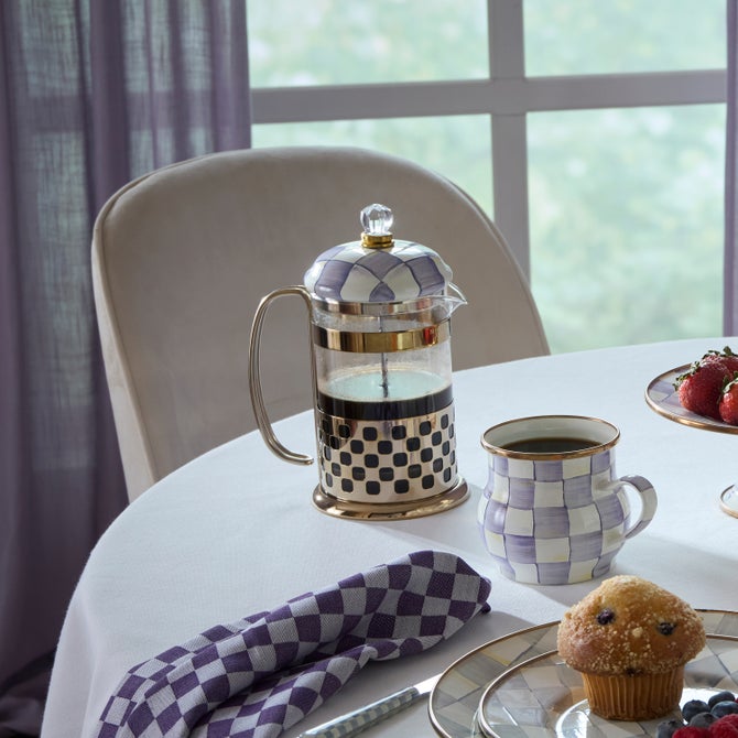 Violet check French press coffee maker with a cylindrical glass body.