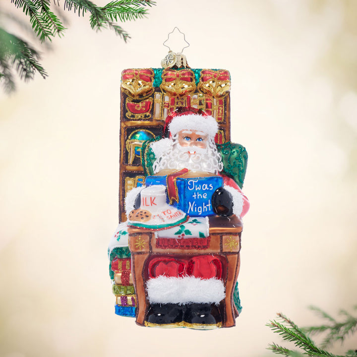 Glass ornament of Santa reading 'Twas the Night, with milk and cookies.