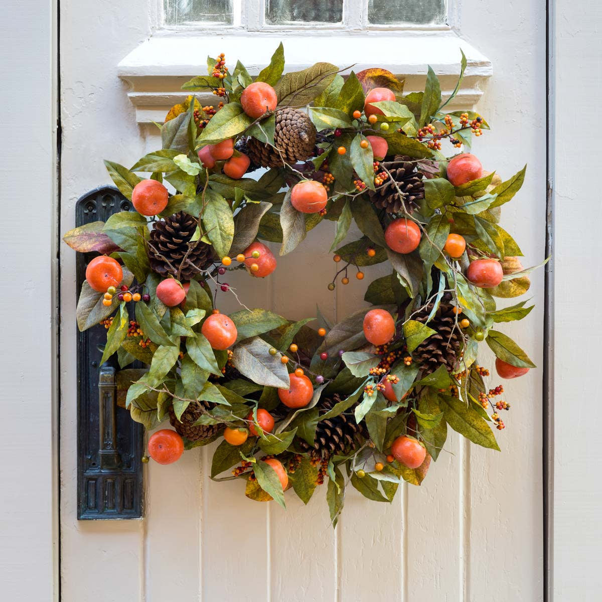 Autumn wreath with polyester foliage in green, orange, red, yellow, and brown featuring pinecones and persimmons.