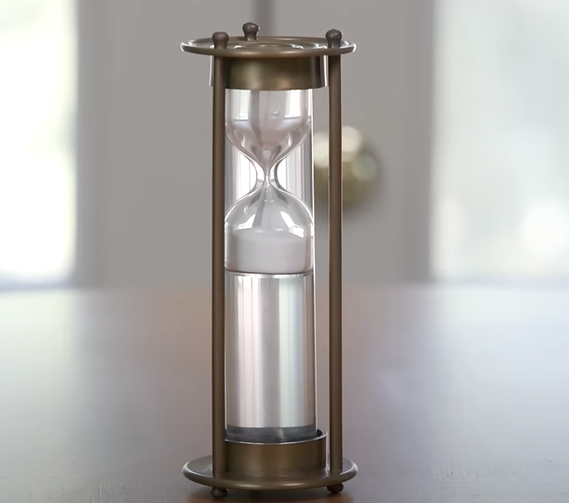 Antique brass sand timer with patina finish featuring a classic hourglass silhouette.