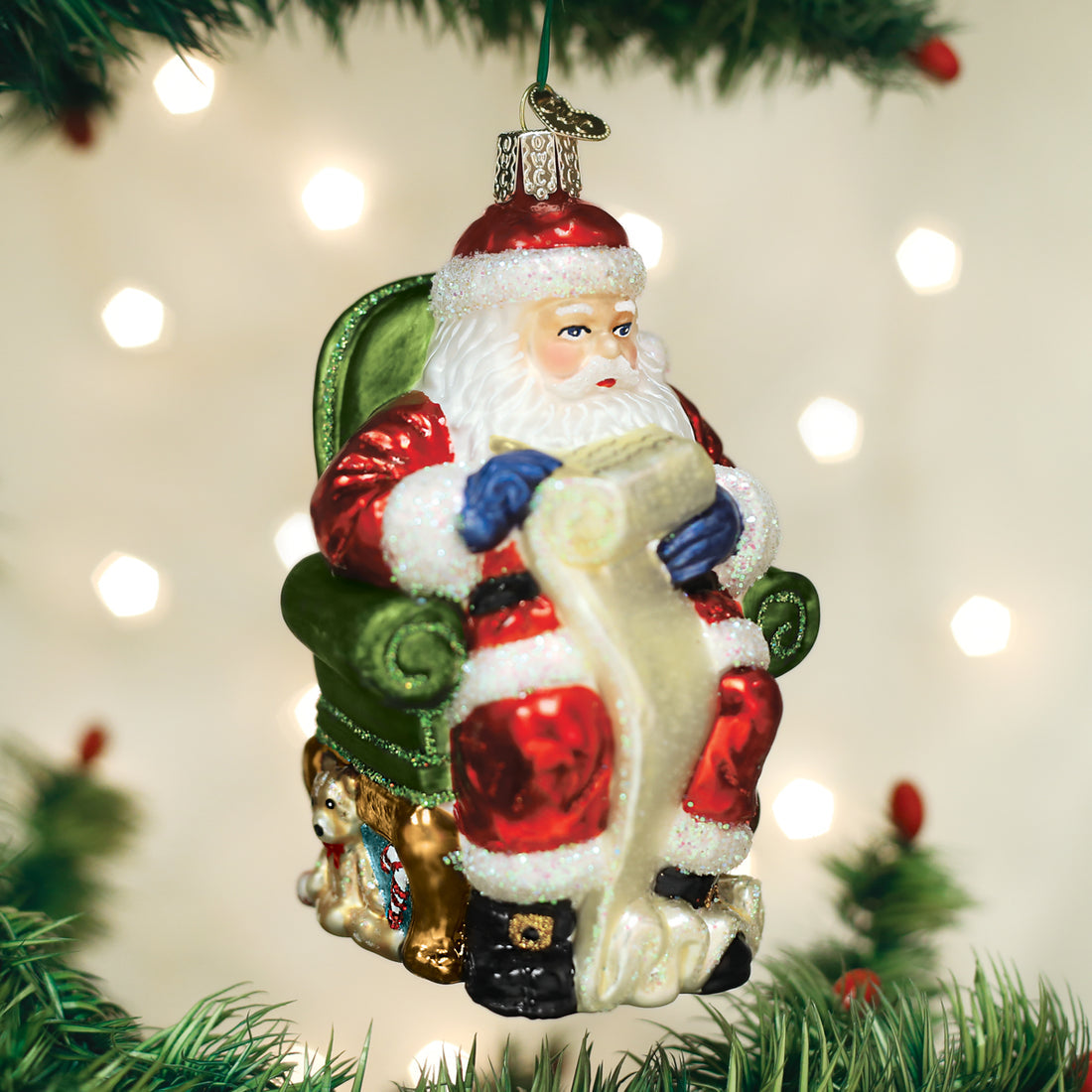 Santa Checking His List glass ornament, hand-painted Santa in a green chair with a long list.
