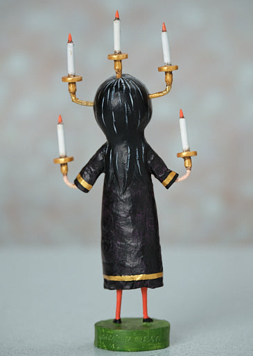 Poly resin Candle Maker figurine with black hair and robe, holding five candles, 8 inches tall.