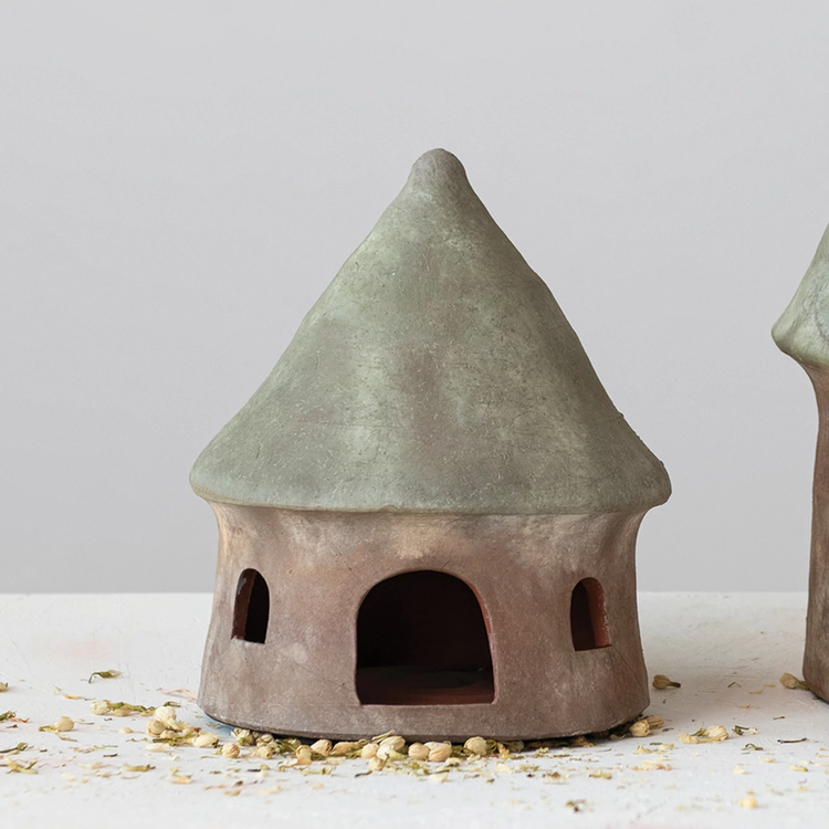 Terra-cotta toad house with a green conical roof and natural brown base with arched openings.