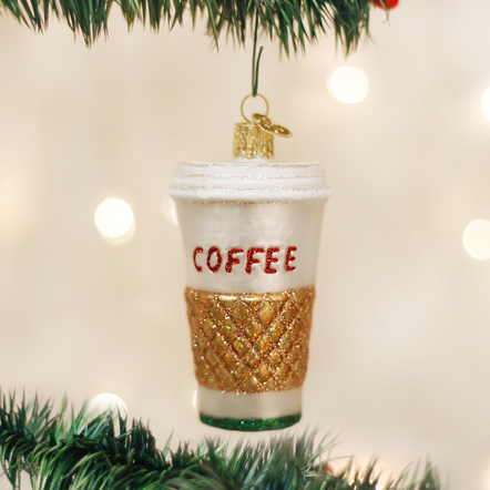 Glass coffee to go cup ornament with a gold glitter sleeve and red 'COFFEE' text on a tree.