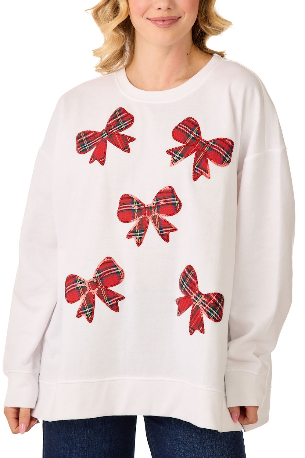 Woman wearing a white long-sleeve sweatshirt featuring five red tartan plaid sequined bows.