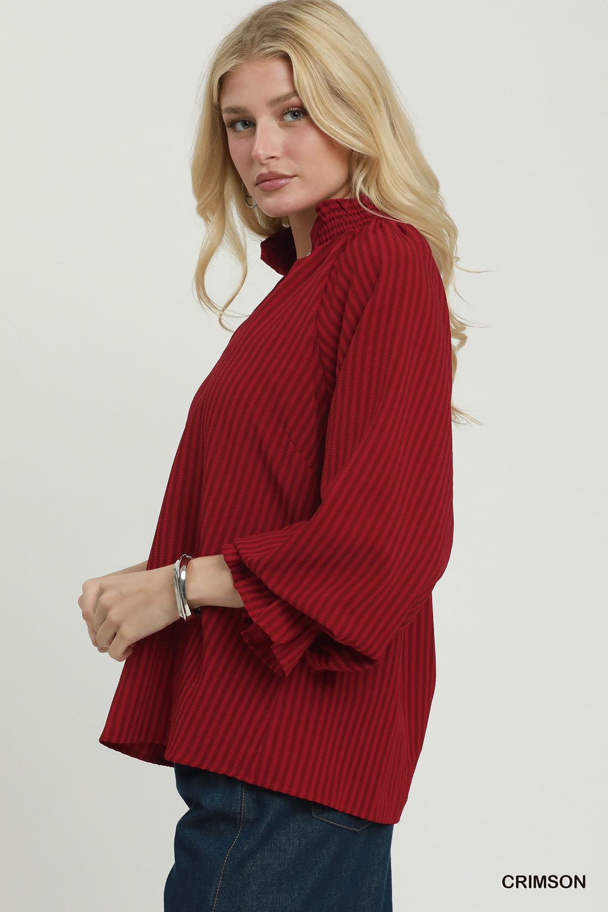 Woman wearing a crimson Emma Stripe Split Neck Blouse with a ruffle collar and long sleeves.