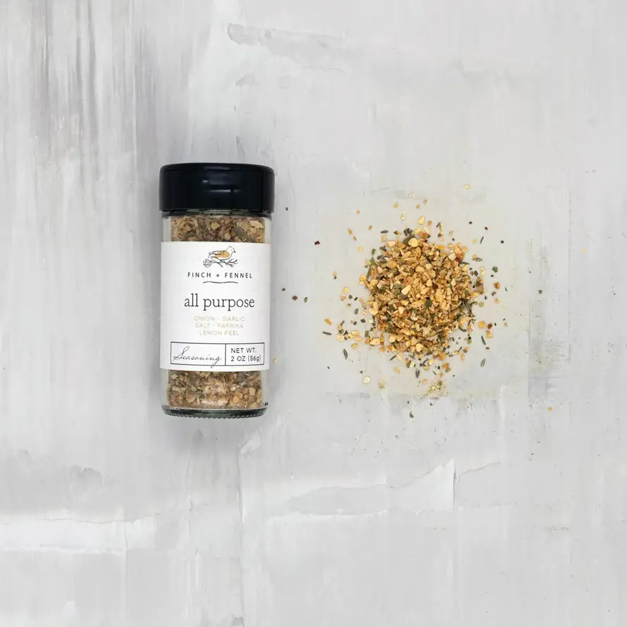 Finch + Fennel All Purpose Seasoning bottle next to a small pile of the spice blend.