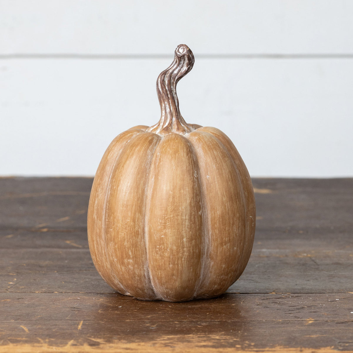 7.25 inch brown resin pumpkin with a textured finish and curved stem on a wooden surface.