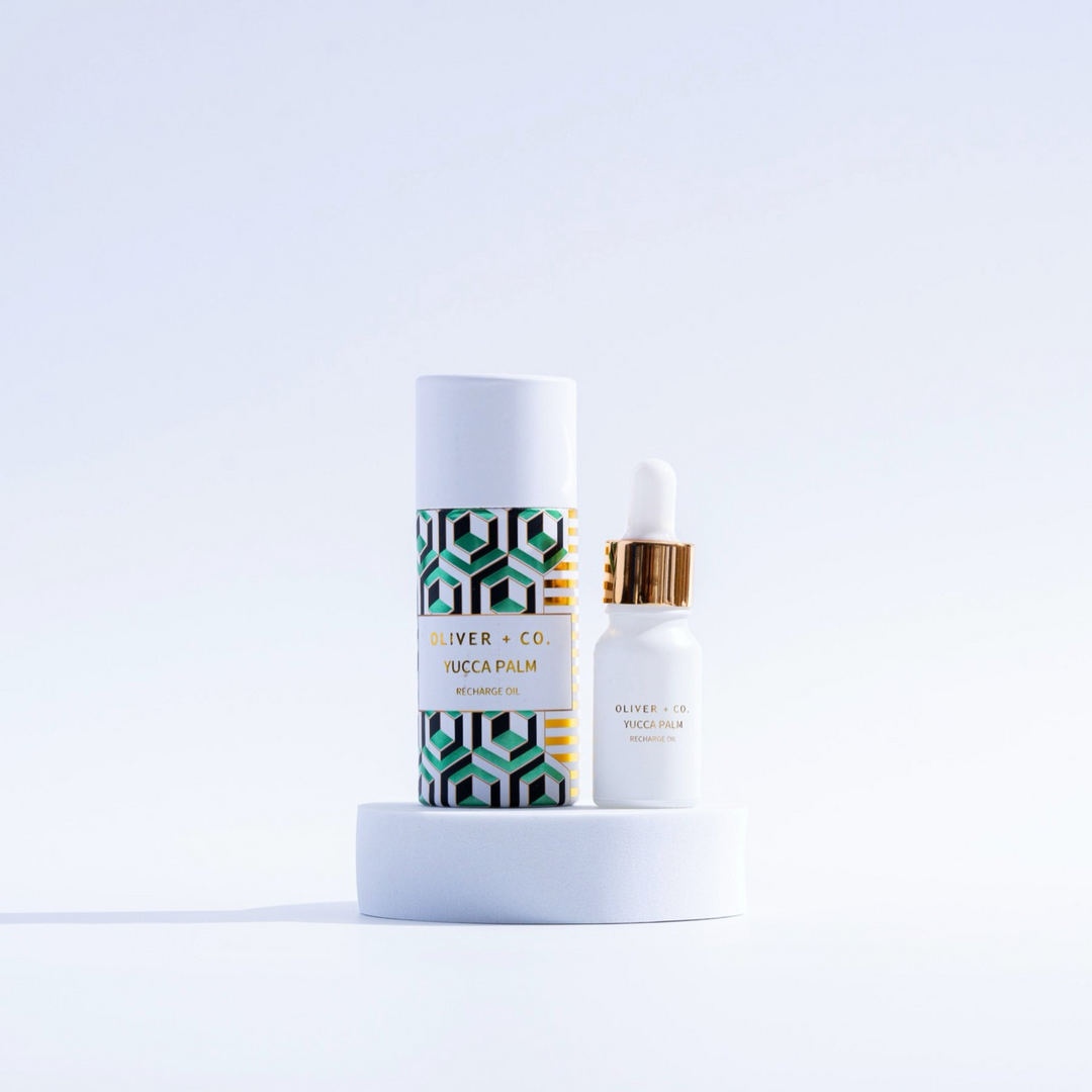 Oliver + Co. Yucca Palm Recharge Oil in a white dropper bottle next to its patterned tube packaging.