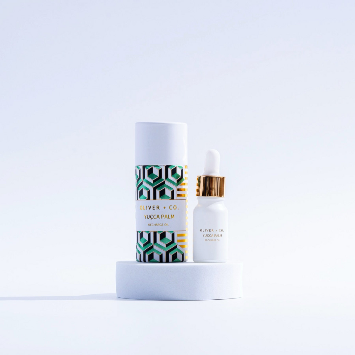 Oliver + Co. Yucca Palm Recharge Oil in a white dropper bottle next to its patterned tube packaging.