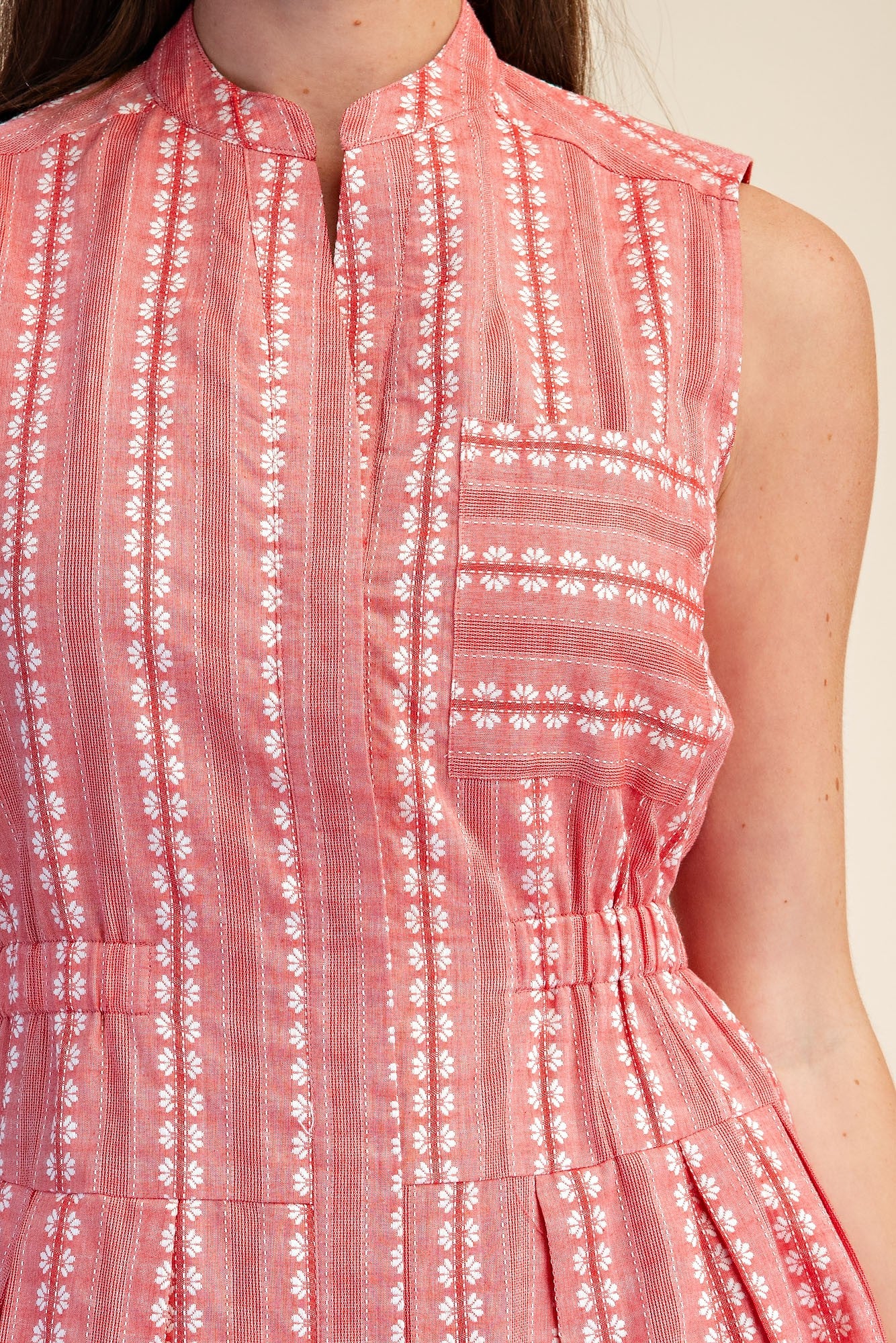Close-up of a sleeveless red and white embroidered boho shirt dress with a cinched waist.