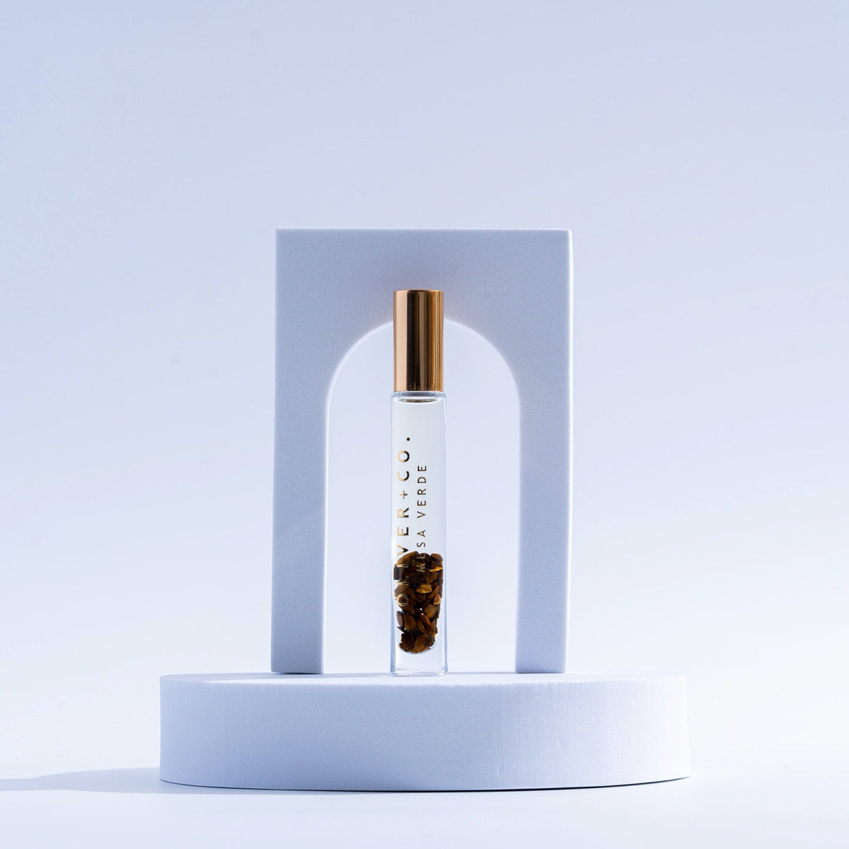 Bougie Stick Mesa Verde roll-on perfume with gold cap and crystals inside, on a white pedestal.