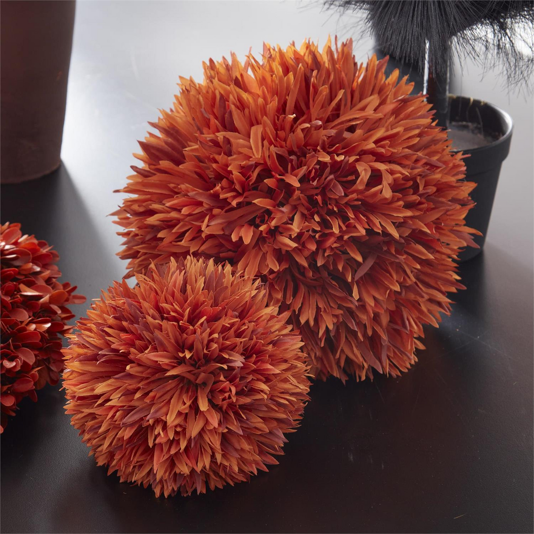 Two orange allium balls of different sizes with textured fabric petals on a dark surface.