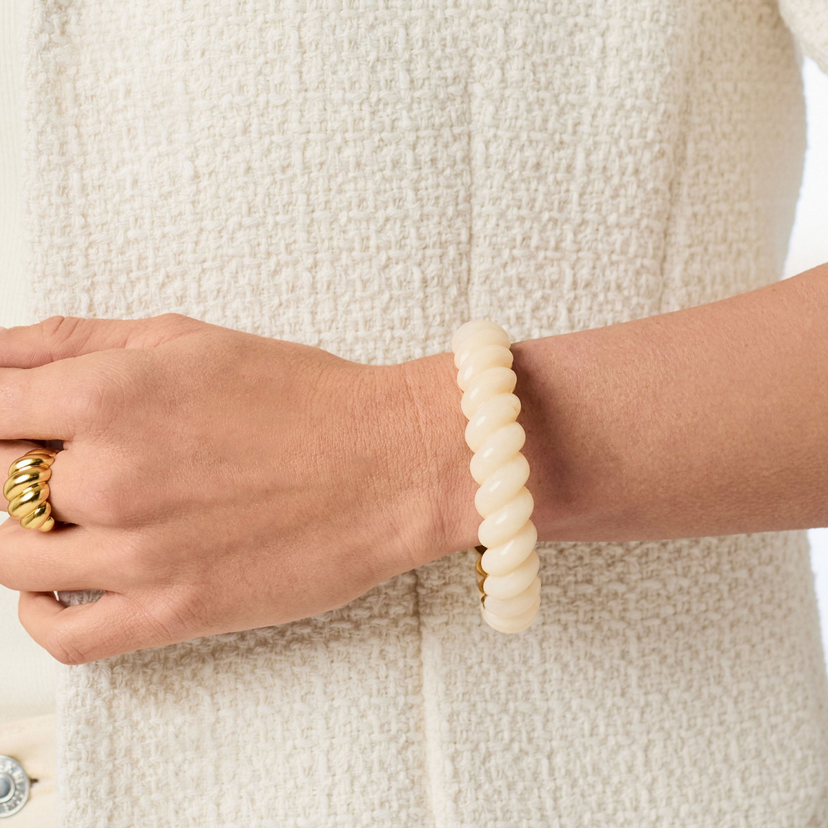 A person wearing the Ravello Statement Bangle, a cream-colored twisted resin bracelet.
