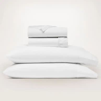 White queen size organic cotton sheet set with signature hemmed edges displayed on a bed.