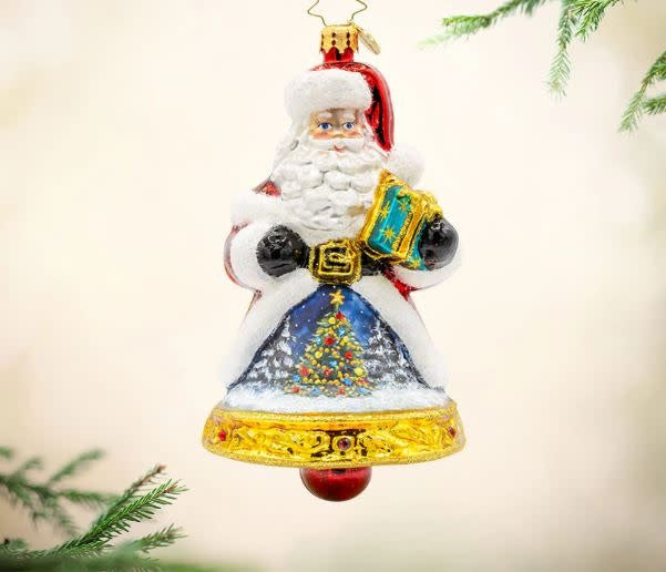 Hand-painted Santa ornament with festive bell, gift bag, snowy village scene on coat.