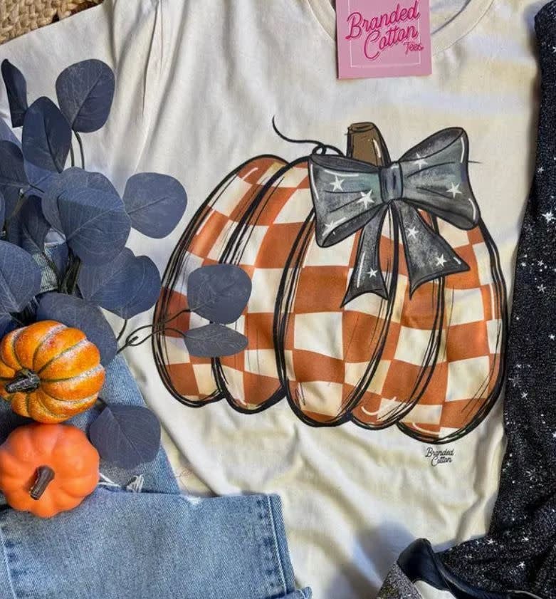 Soft black t-shirt with a checkered pumpkin bow graphic on the chest.
