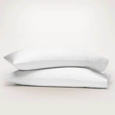 White organic cotton hemmed pillowcase set on a king-sized bed.