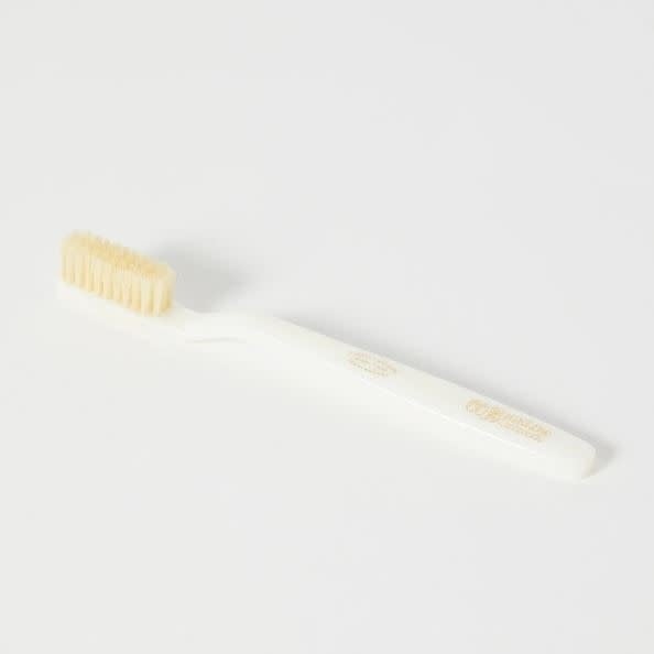Medium ivory natural boar bristle toothbrush with a smooth handle.
