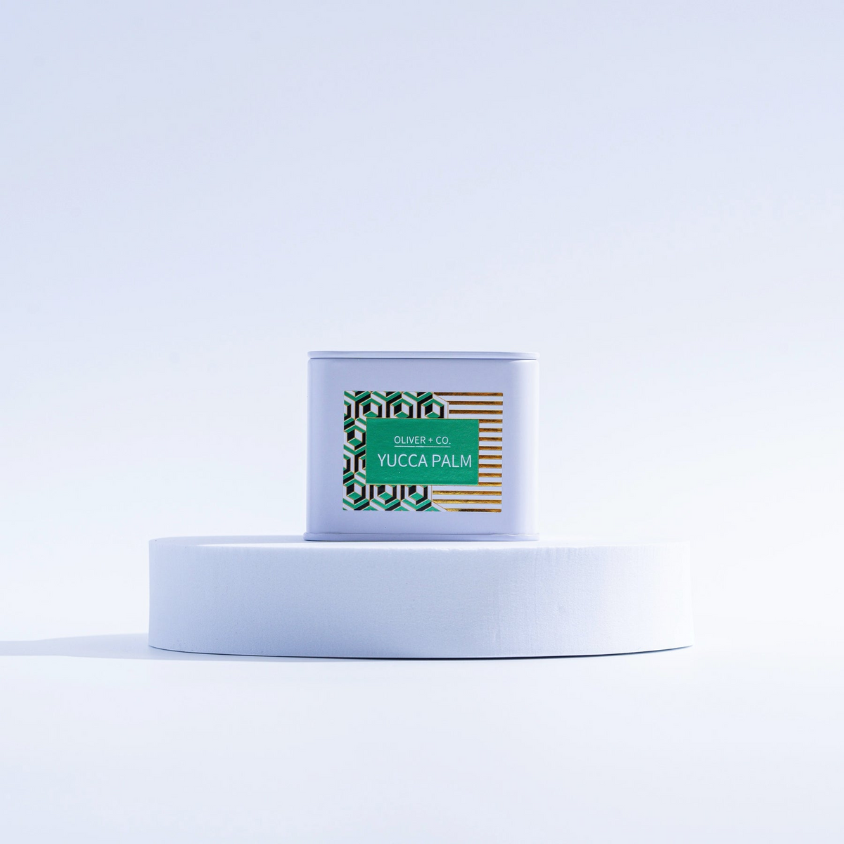 Yucca Palm Travel Companion Candle in a white tin on a circular white pedestal.