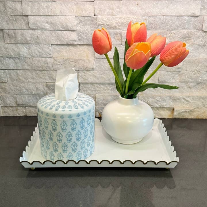 Blue and white patterned ceramic tissue vessel on a white tray next to a vase of orange tulips.