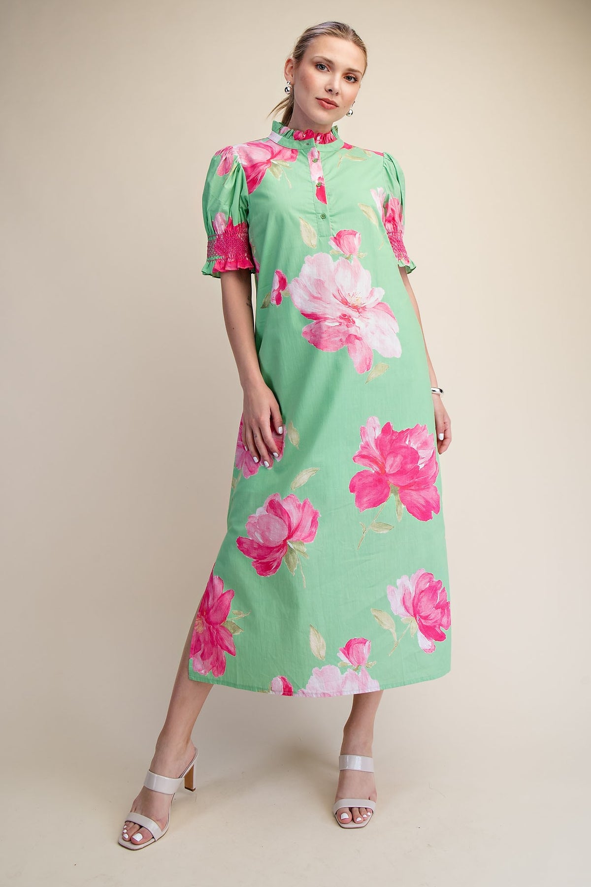 Woman in a green Megan midi dress with pink floral print, ruffle neck, and puff sleeves.