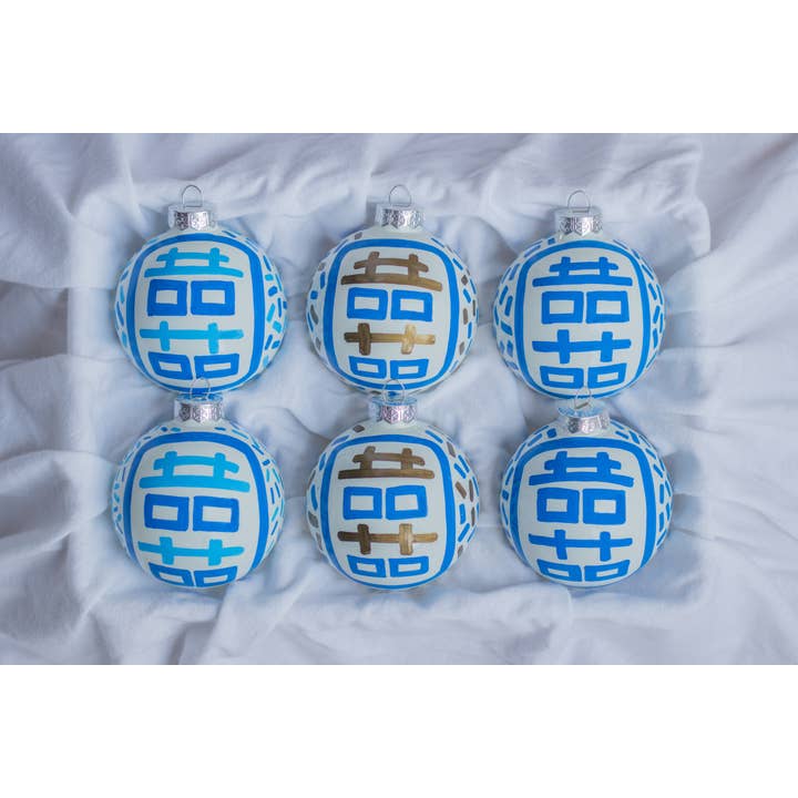 Hand-painted ceramic ornament featuring a red double happiness symbol on a white spherical surface.