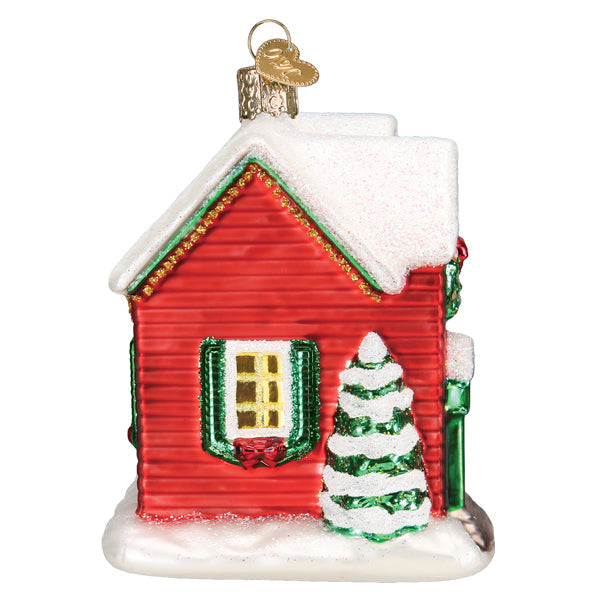 Red glass house ornament with snow-covered roof, green shutters, and a glittery Christmas tree.